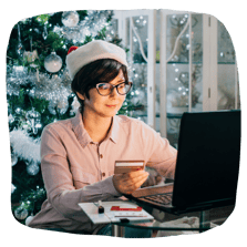 Woman in Santa hat buying an online small business gift card in front of christmas tree